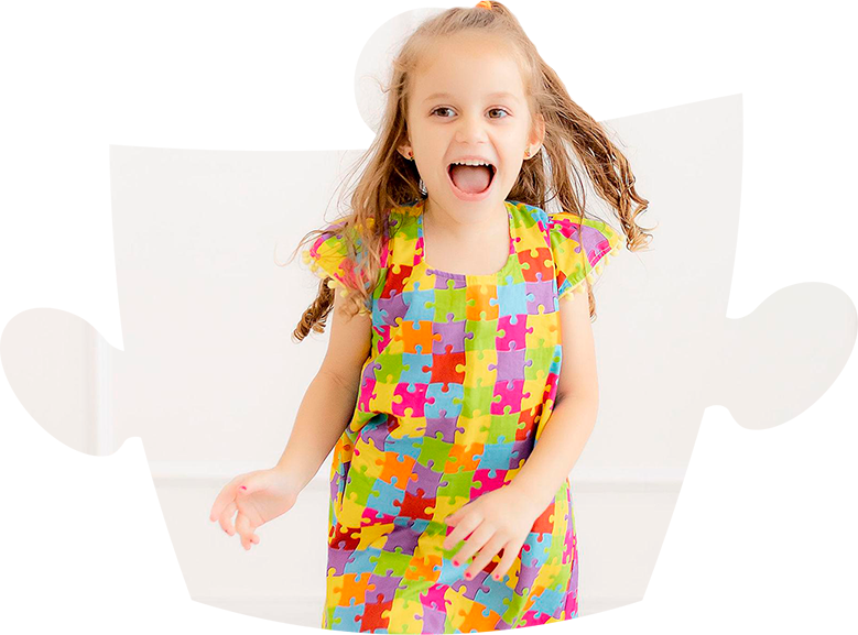 Criança sorridente vestindo roupa colorida com estampa de quebra-cabeça